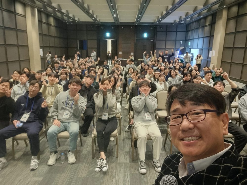 전국 단체 행사 강당에서 회원들이 모여 앉은 앞에서 마이크를 든 MC 신용주
