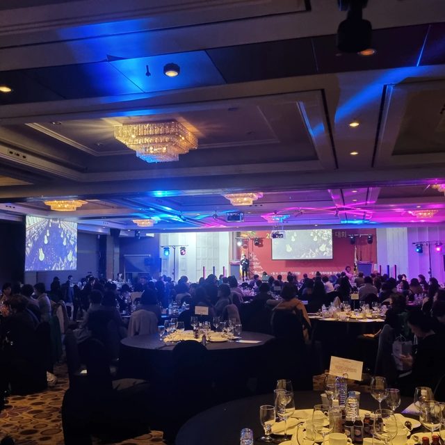 전국 호텔 연회장 행사에서 조명이 켜진 무대와 만찬 테이블