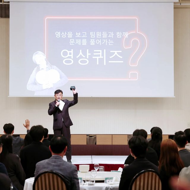 전국 송년회 영상퀴즈 코너에서 스크린 앞에 선 MC와 참석자들