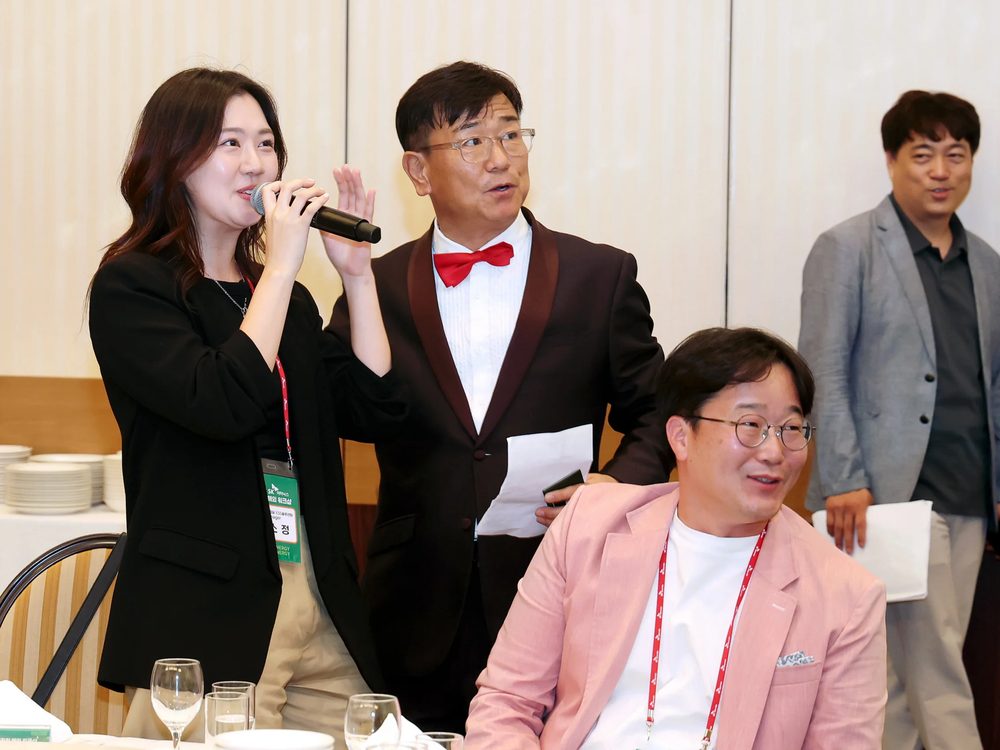 전국 송년회 행사에서 진행자와 참석자들이 함께 마이크를 들고 코너를 진행하는 모습